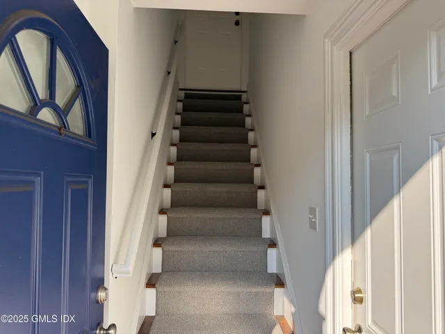 a view of staircase with lots of frames on wall and a window