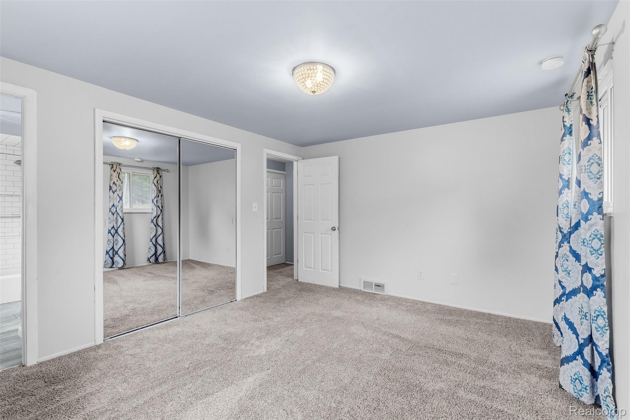 819 Alpine Trail Fenton, MI 48430 - Photo 18 of 41 Mirrored sliding closet doors with carpeting, white paneled doors, and a decorative flush-mount ceiling light