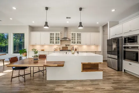 a large kitchen with kitchen island a large counter top stainless steel appliances and cabinets