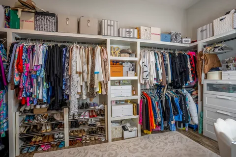 a view of walk in closet with clothes and shoes