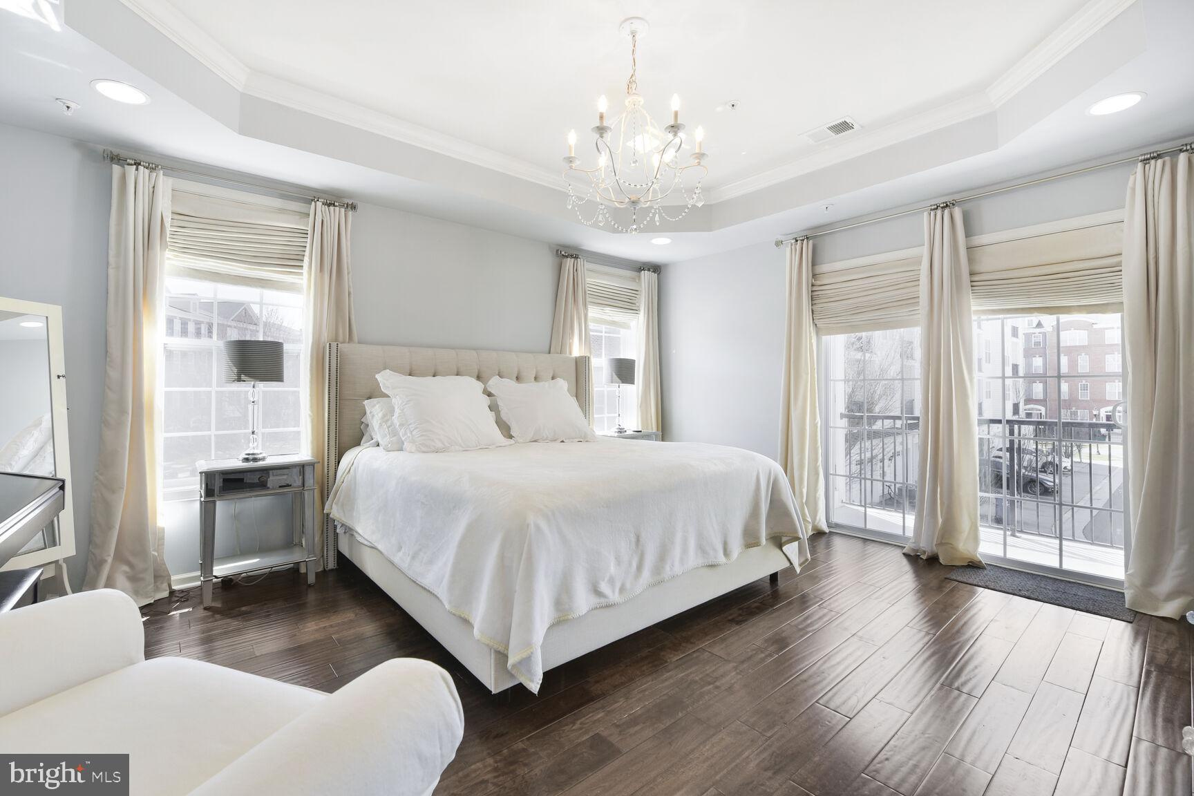 43037 Clarks Mill Terrace Ashburn, VA 20148 - Photo 21 of 28 a bedroom with a large bed and a chandelier