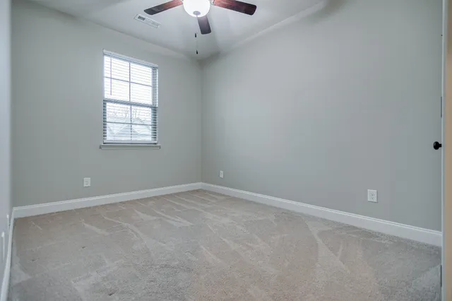 an empty room with a chandelier fan and windows
