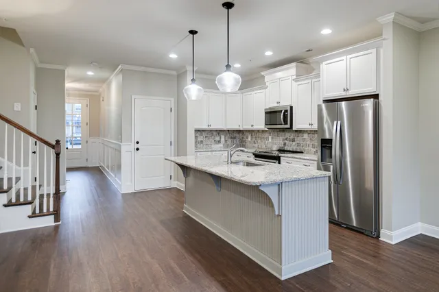 a large kitchen with stainless steel appliances kitchen island a large counter top a sink a refrigerator and a stove