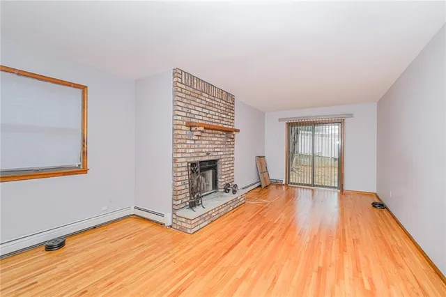 a view of empty room with wooden floor and fireplace