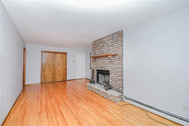 a view of empty room with wooden floor and fireplace
