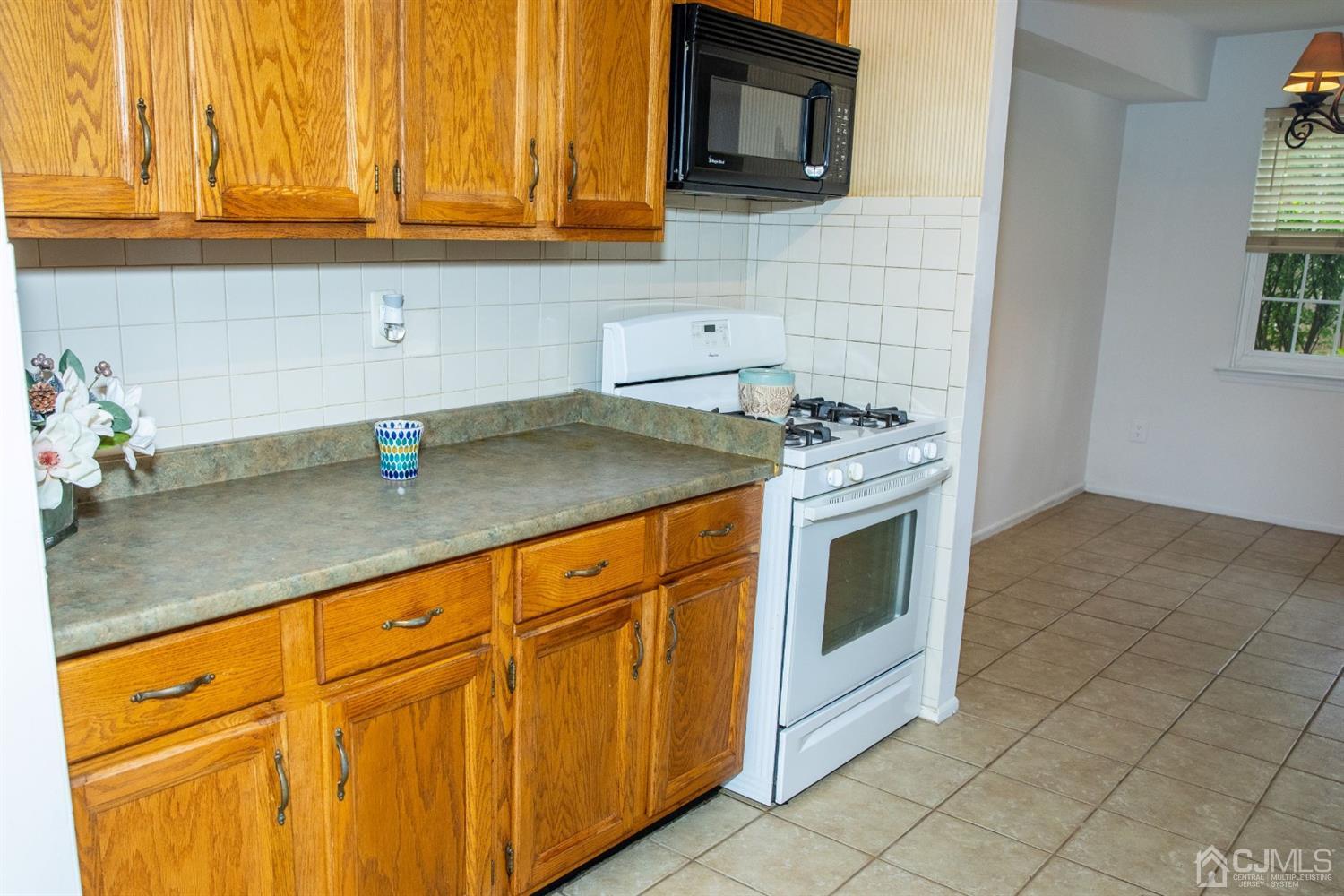 111 Keystone Court, Unit A Woodbridge, NJ 07095 - Photo 16 of 33 a kitchen with granite countertop stainless steel appliances a stove a sink and a microwave