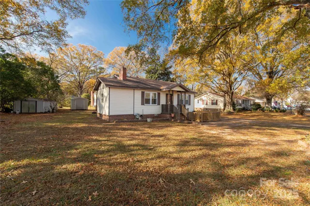a backyard of a house with large trees and outdoor seating