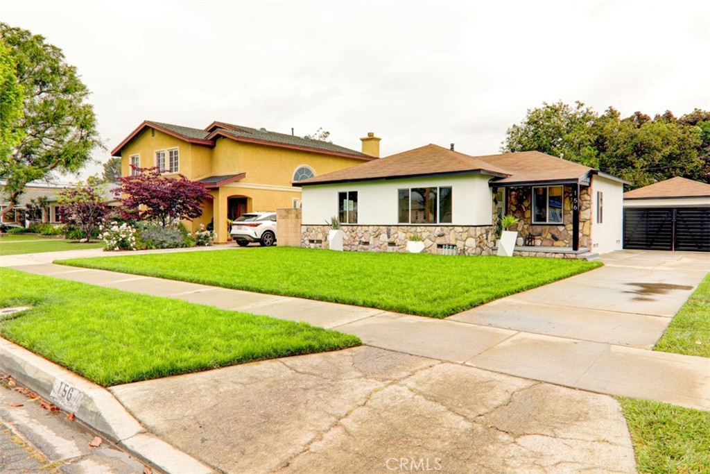 a front view of a house with a yard and potted plants