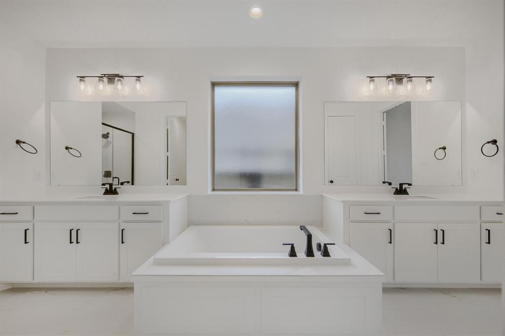 242 Buffalo Boulevard Rhome, TX 76078 - Photo 25 of 28 a bathroom with a bathtub a double vanity sink and mirror