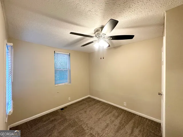 an empty room with a window and a fan