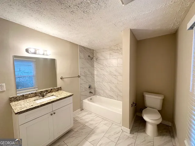 a bathroom with a granite countertop toilet a sink and bathtub