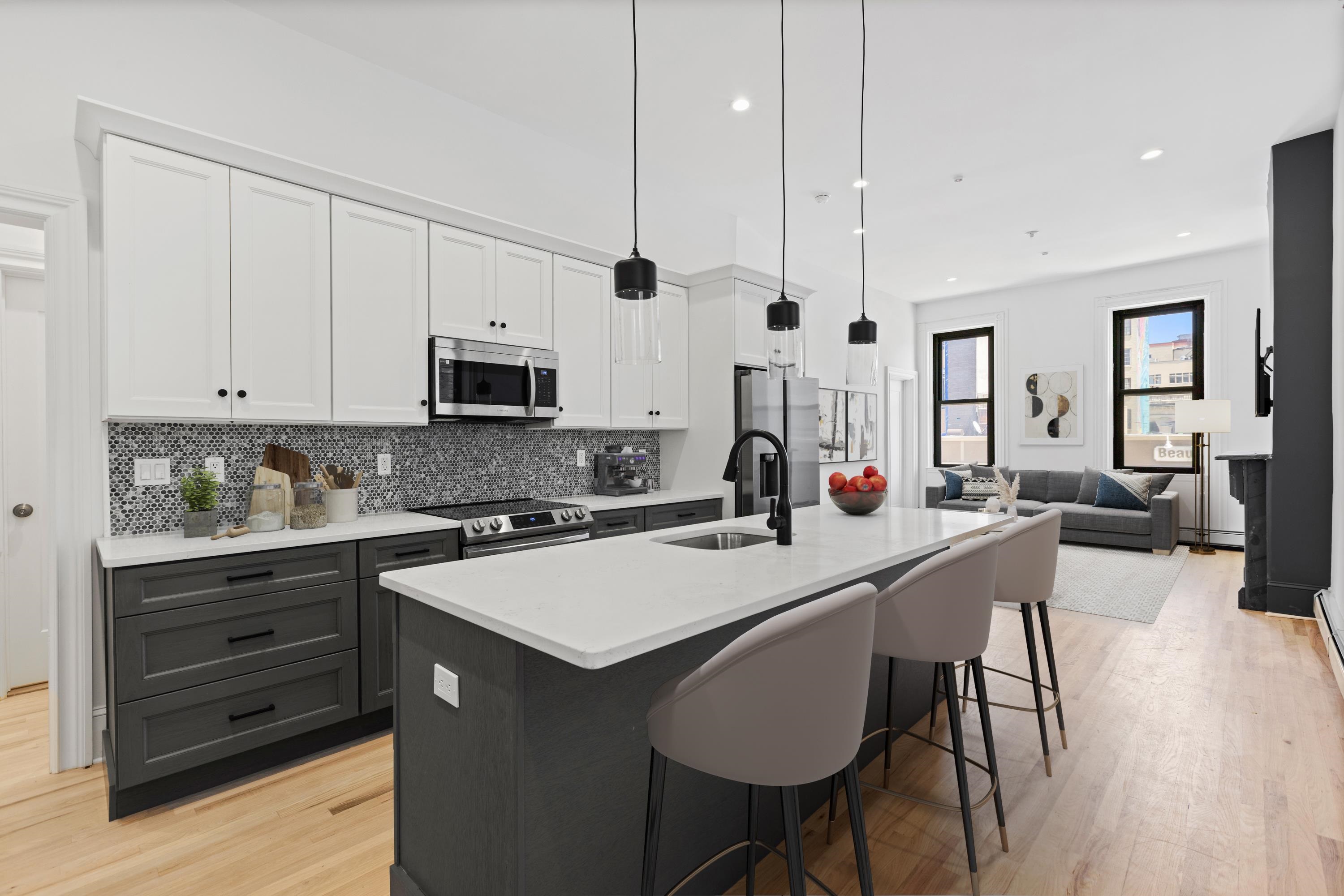 a kitchen with stainless steel appliances a stove a sink a microwave a refrigerator white cabinets and wooden floor
