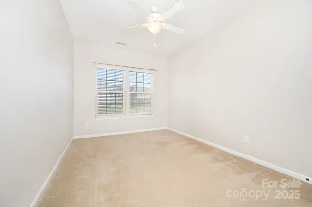 an empty room with a window and a fan