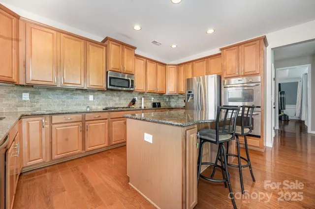 a kitchen with stainless steel appliances granite countertop wooden cabinets a stove top oven a sink and dishwasher