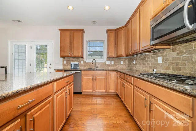 a large kitchen with stainless steel appliances granite countertop a stove a sink and a microwave