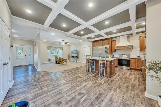 a kitchen with stainless steel appliances kitchen island granite countertop a refrigerator a sink a stove and cabinets