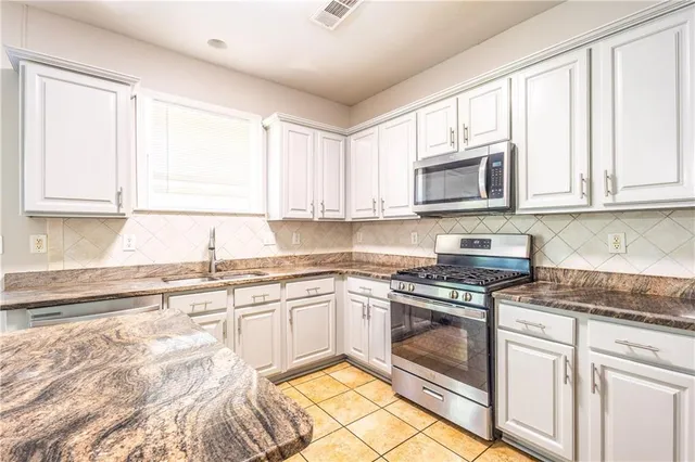 a kitchen with granite countertop cabinets stainless steel appliances a sink and a window