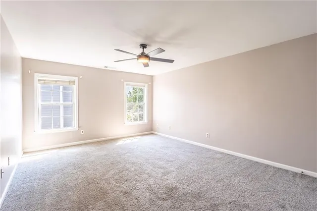 an empty room with windows and ceiling fan