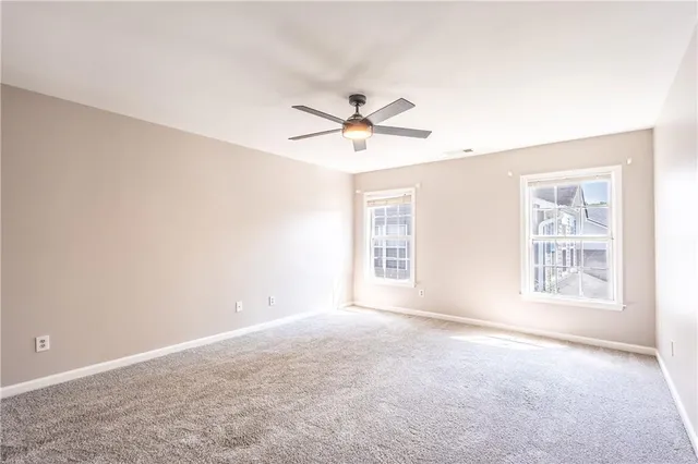 an empty room with chandelier fan and windows