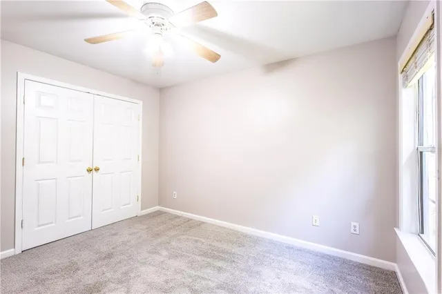 an empty room with a chandelier fan and windows