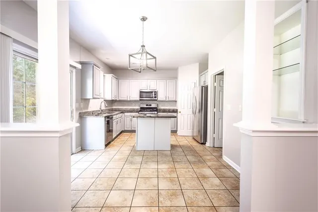 a kitchen with stainless steel appliances kitchen island granite countertop a refrigerator a sink dishwasher a stove and white cabinets with wooden floor