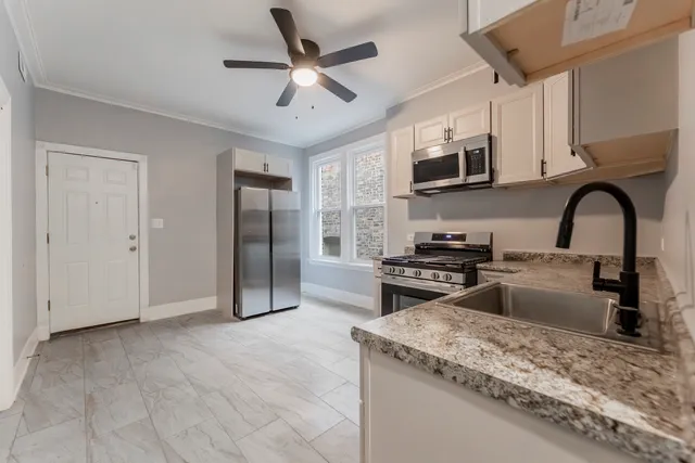 a kitchen with stainless steel appliances granite countertop a stove top oven a sink a refrigerator with a dining table and chairs