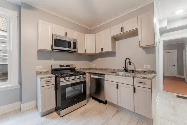 a kitchen with stainless steel appliances granite countertop white cabinets a sink a stove and a microwave