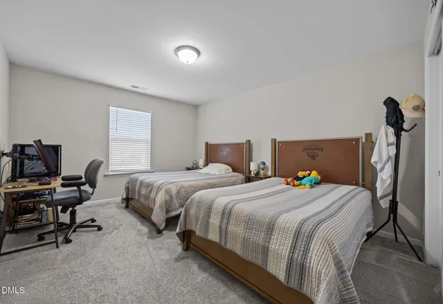 a bedroom with a bed a computer on the desk and a chair