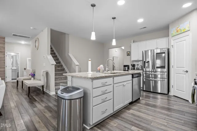 a kitchen with stainless steel appliances granite countertop a sink a stove a refrigerator cabinets and chairs