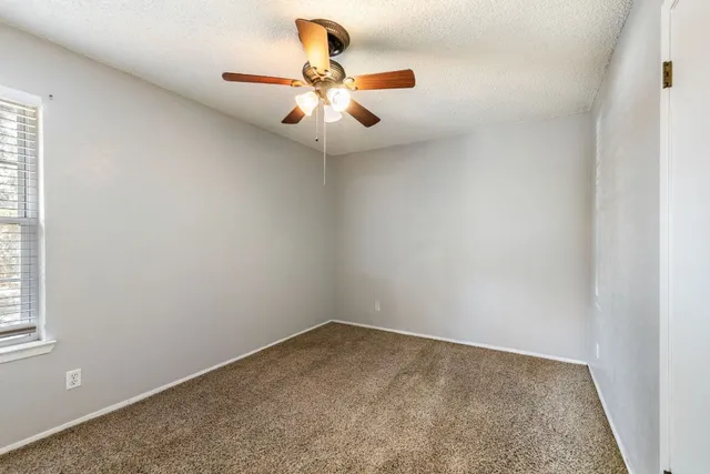 an empty room with a window and a fan