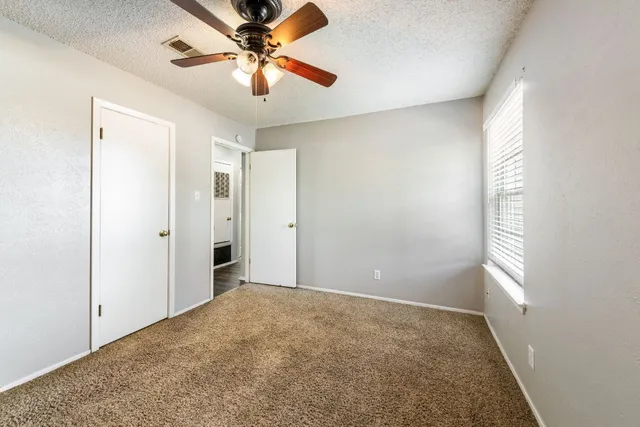 an empty room with windows and fan