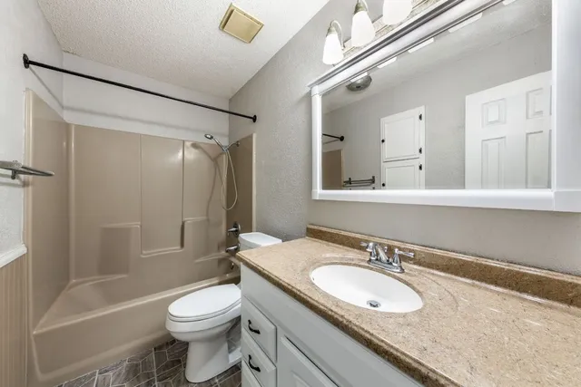 a bathroom with a granite countertop sink toilet and shower