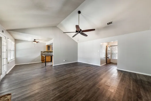 a view of an empty room with wooden floor ceiling fan