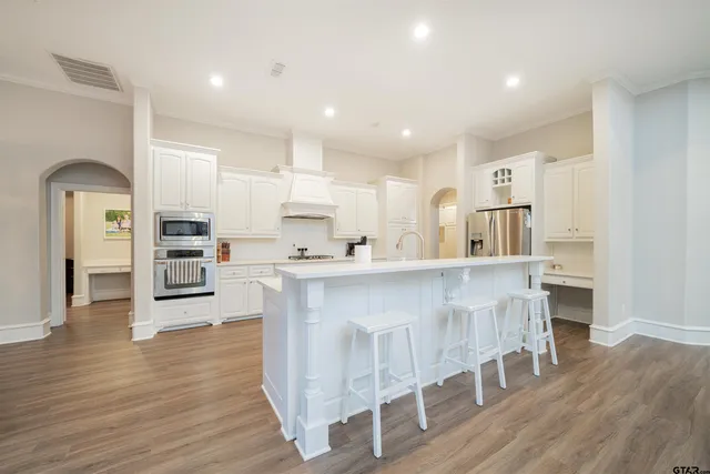 a kitchen with stainless steel appliances a dining table chairs and wooden floor