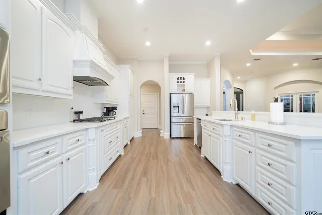 a large kitchen with cabinets wooden floor and stainless steel appliances
