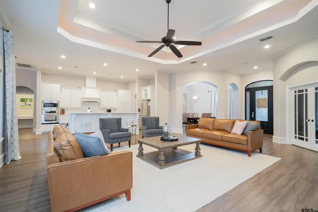 a living room with furniture kitchen view and a chandelier