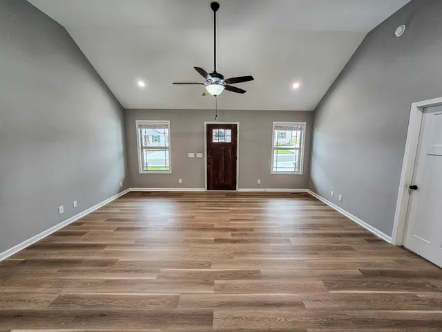 a view of an empty room with window and wooden floor