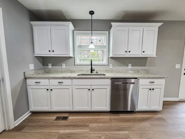 a kitchen with granite countertop white cabinets white appliances and a sink