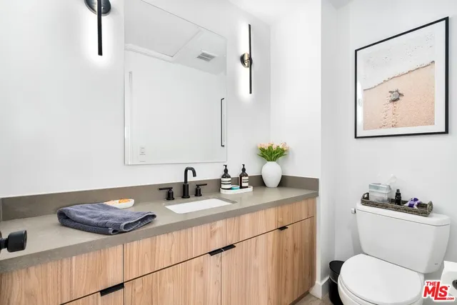 a bathroom with a granite countertop sink and a toilet
