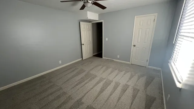 an empty room with a window and a ceiling fan