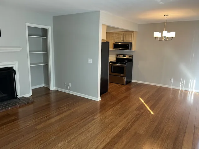 an empty room with wooden floor kitchen appliances and cabinets