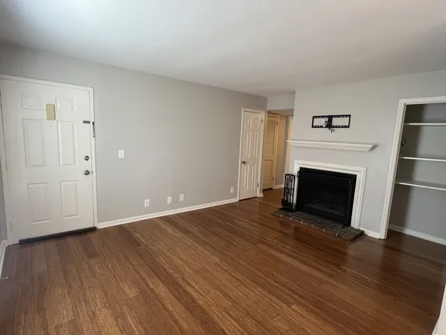 a view of empty room with wooden floor and fireplace