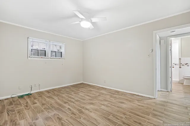 a view of empty room with wooden floor and ceiling fan
