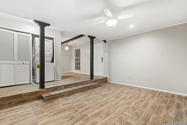 an empty room with wooden floor and a ceiling fan