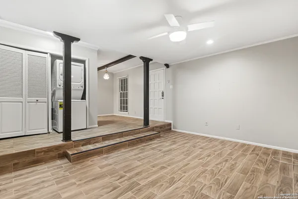 an empty room with wooden floor and a ceiling fan