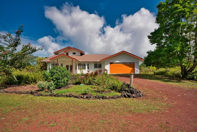 a front view of a house with a yard and potted plants