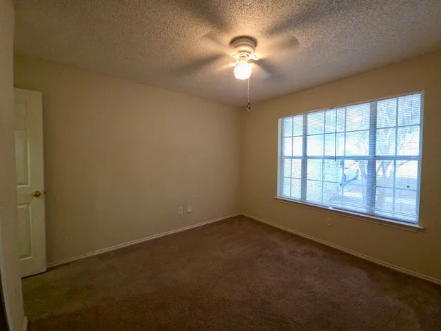 an empty room with a window and a ceiling fan