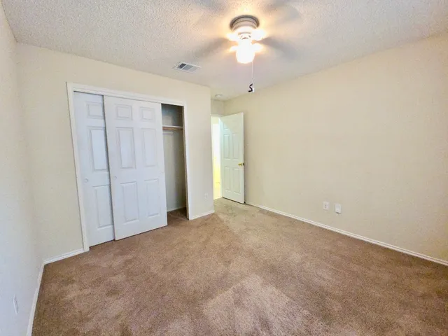 an empty room with a ceiling fan and closet