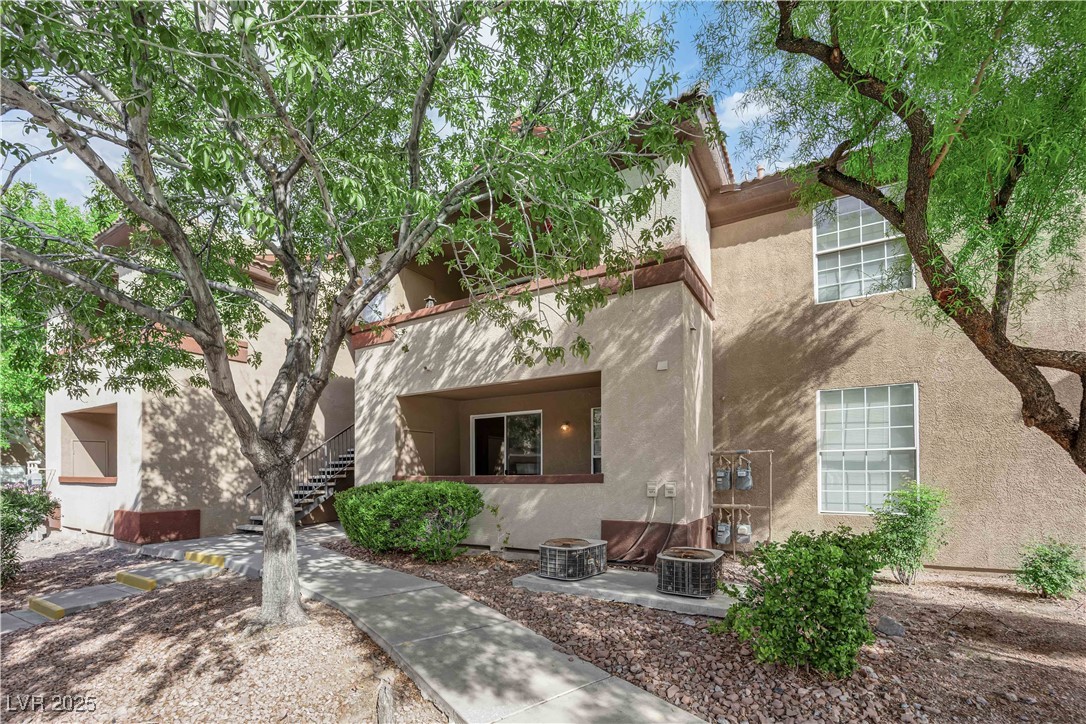 Rear view of property with stairs, stucco siding, an outdoor fire pit, and a patio