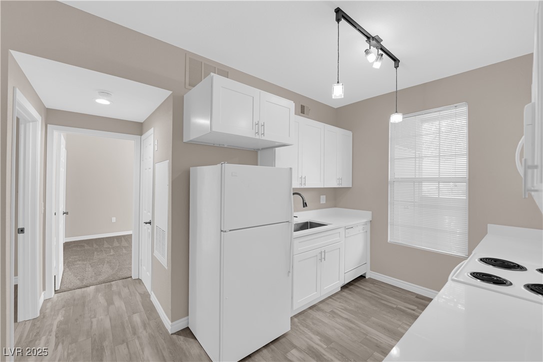 231 West Horizon Ridge Parkway, Unit 1313 Henderson, NV 89012 - Photo 10 of 20 Kitchen with white appliances, white cabinetry, light countertops, light wood-style floors, and decorative light fixtures